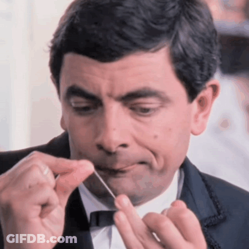 Man In Tuxedo Holding String In Mouth GIF