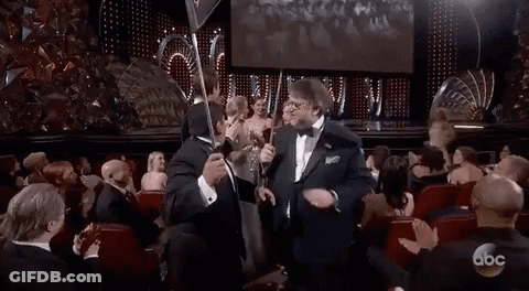 Man In Tuxedo Holding Trophy At Awards Show GIF