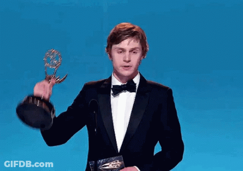 Man In Tuxedo Holding Trophy At Microphone GIF