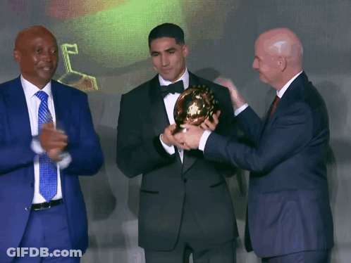 Man In Tuxedo Holding Trophy Two Men Applaud GIF