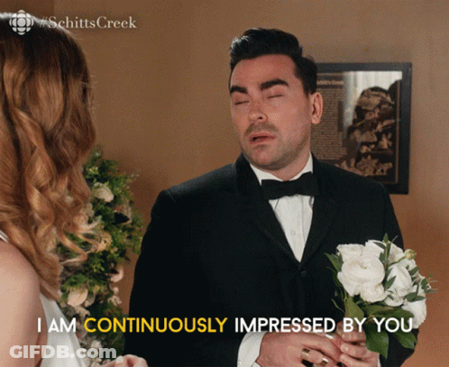 Man In Tuxedo Holding White Flowers Says I Am Continuously Impressed By You GIF