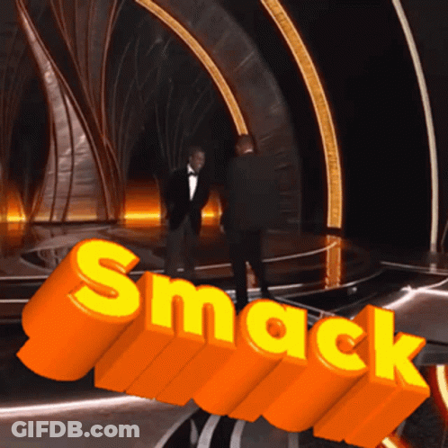 Man In Tuxedo In Front Of Orange Smack Sign GIF