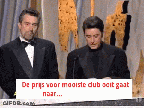 Man In Tuxedo Next To Man With Sign De Prijs Voor Mooiste Club Ooit Gaat GIF