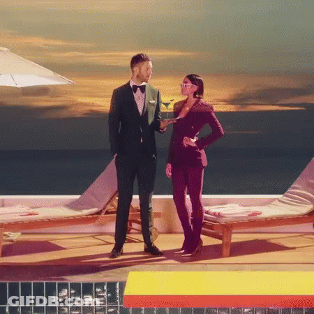 Man In Tuxedo Next To Woman Holding Martini GIF