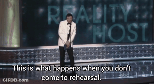 Man In Tuxedo On Stage With Reality Host Sign GIF