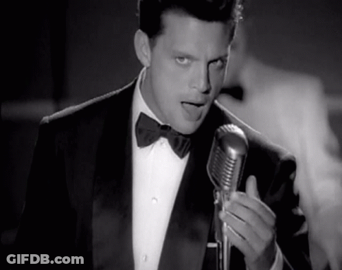 Man In Tuxedo Singing Into Microphone GIF