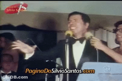 Man In Tuxedo Singing Into Microphone With Paginadossilviosantos.com GIF