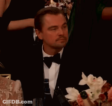Man In Tuxedo Sitting At Table Pointing GIF