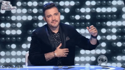 Man In Tuxedo Sitting With Hand On Chest GIF