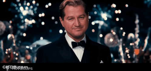 Man In Tuxedo Smiling In Front Of Fandango Movie Clip GIF
