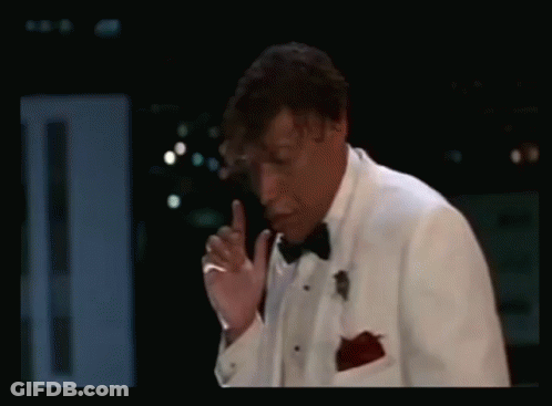 Man In Tuxedo Smoking Cigarette In Dark Room GIF