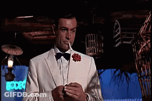 Man In Tuxedo Smoking In Dark Room GIF