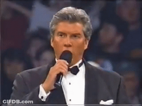 Man In Tuxedo Speaking Into Microphone GIF