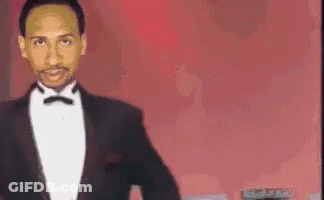 Man In Tuxedo Standing Before Red Background GIF