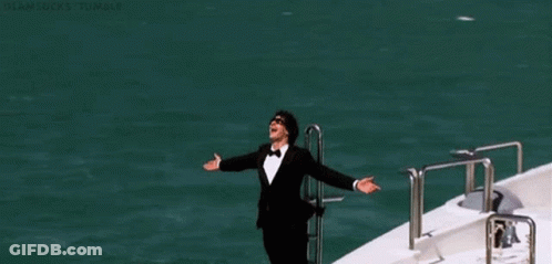 Man In Tuxedo Standing In Front Of White Yacht GIF