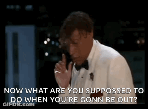 Man In Tuxedo Talking On Phone With Finger To Lips GIF