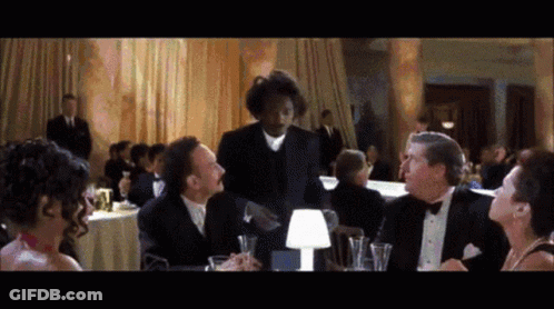 Man In Tuxedo Talking To Group At Tables GIF
