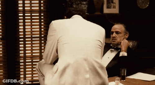 Man In Tuxedo Talking To Man In White Suit GIF