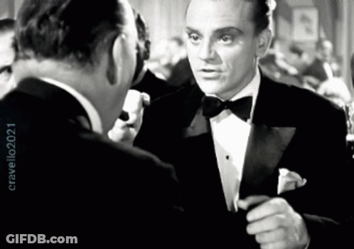 Man In Tuxedo Talks To Another Man In Black And White Photo GIF