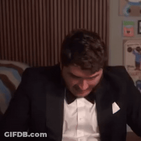 Man In Tuxedo With Bow Tie Sitting On Bed GIF
