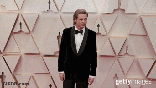 Man In Tuxedo With Oscar Statues GIF