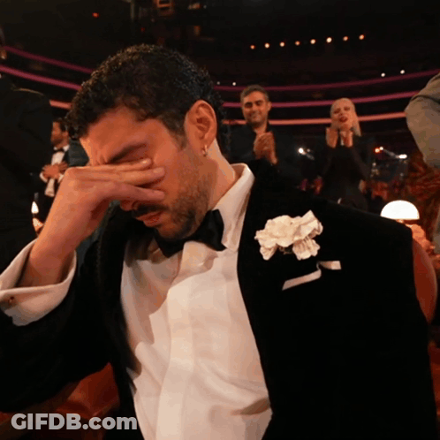 Man In Tuxedo With White Flower Covering Face GIF