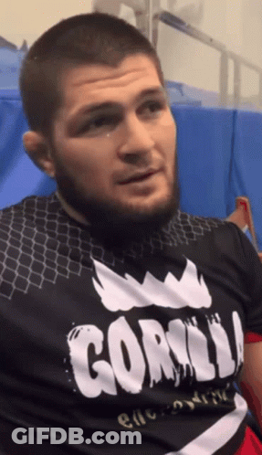Man In UFC Hat Standing In Front Of Makhachev Time Sign GIF