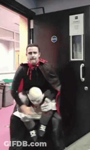 Man In Vampire Costume Carrying Man In White Mask GIF