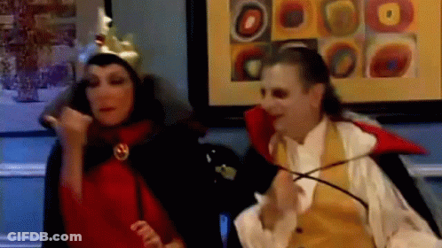 Man In Vampire Costume Next To Woman In Crown GIF