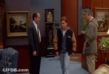 Man In Varsity Jacket Talking To Two Men GIF