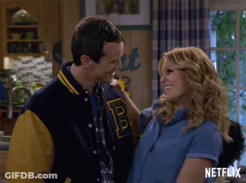 Man In Varsity Jacket With B Hugging Woman GIF