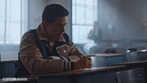 Man In Varsity Jacket With Letter P Sitting At Desk GIF
