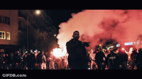 Man In Venum Shirt Stands Before Protesters GIF