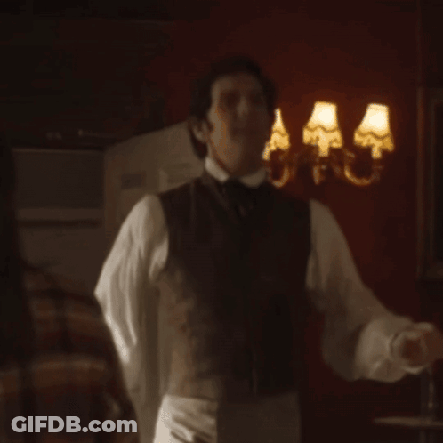 Man In Vest And Tie In Front Of Wall With Three Lamps GIF