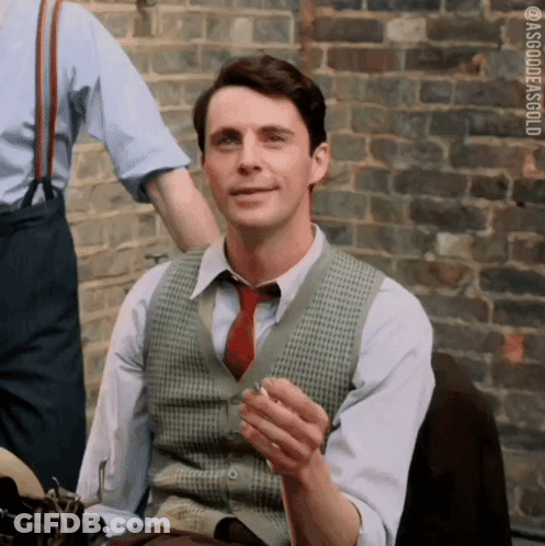 Man In Vest And Tie Smoking By Brick Wall GIF