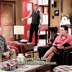 Man In Vest And Tie Talking To Two Men On Couch GIF