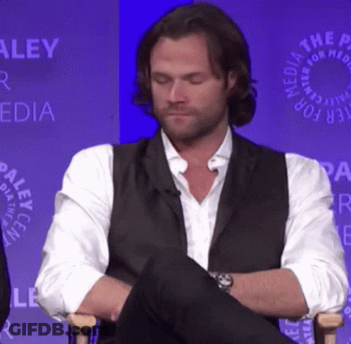 Man In Vest And White Shirt Sitting With Legs Crossed GIF