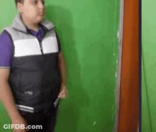 Man In Vest Holding Knife At Green Wall GIF