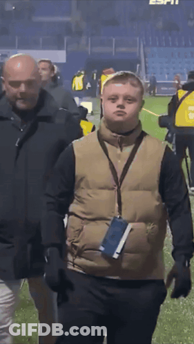 Man In Vest With Lanyard Walking On Field GIF
