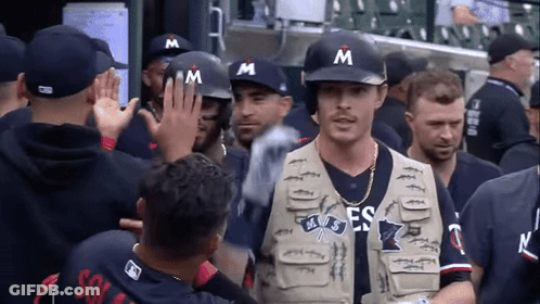 Man In Vest With Letter M Walks Through Crowd GIF