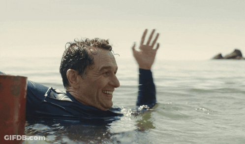 Man In Wetsuit Waving In Ocean GIF