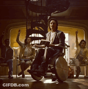 Man In Wheelchair Reading Book Surrounded By People GIF