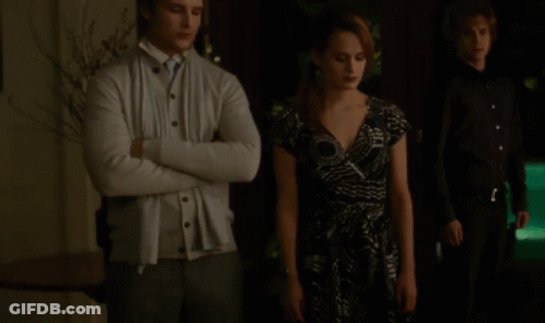 Man In White Cardigan Next To Woman In Dress GIF