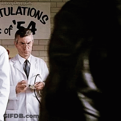 Man In White Coat Standing In Front Of Sign Saying Tulations GIF