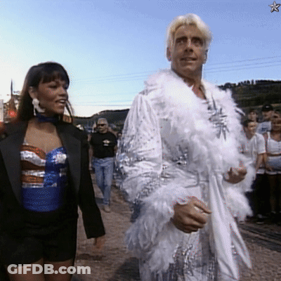 Man In White Feathered Robe Walking With Woman GIF