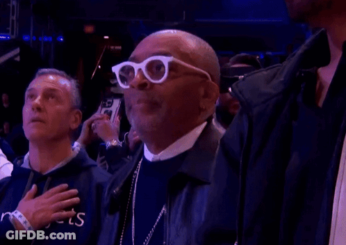 Man In White Glasses With Hand On Heart In Crowd GIF