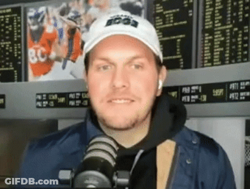 Man In White Hat And Blue Jacket Talking Into Microphone GIF