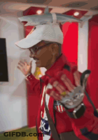 Man In White Hat And Red Jacket Holding Shark Toy On Head GIF