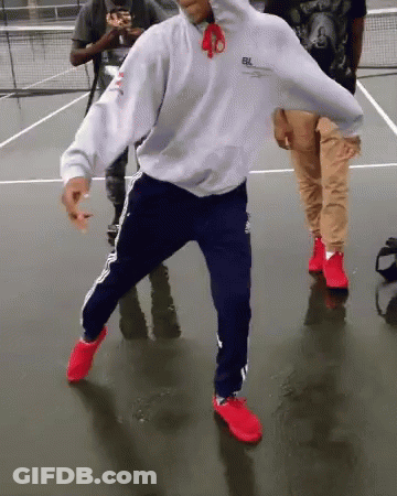 Man In White Hoodie And Blue Pants Dancing On Tennis Court GIF