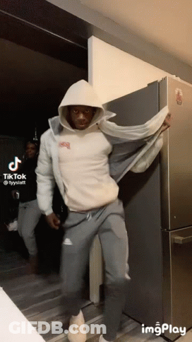 Man In White Hoodie Standing By Refrigerator GIF